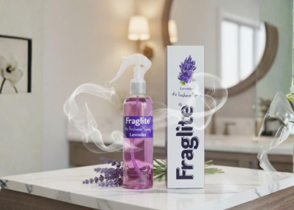 A purple Fraglite lavender spray bottle and white box on a marble countertop in a blurred bathroom setting with lavender sprigs.