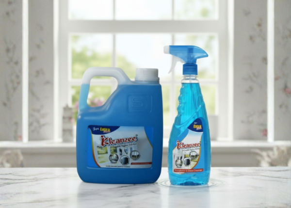 A 5-liter blue gallon container and a 500ml spray bottle of Kleanzee blue liquid glass cleaner on a white marble surface in front of a bright window.