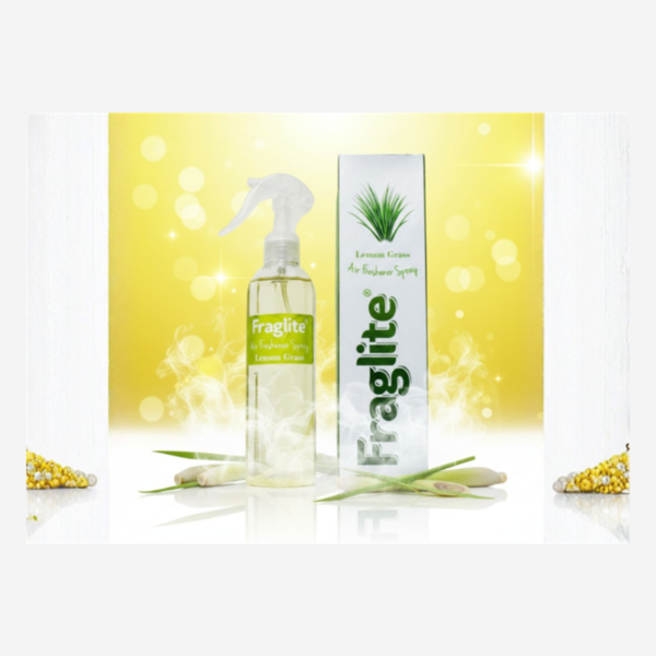 A clear bottle of Fraglite Lemon Grass spray and its box against a vibrant yellow bokeh background with fresh lemongrass stalks at the base.