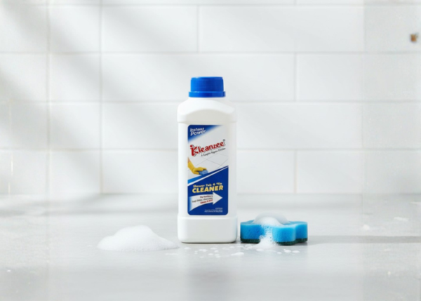 A single white bottle of Kleanzee Shower Tub & Tile Cleaner with a blue cap, positioned on a grey surface with a mound of foam and a blue sponge.