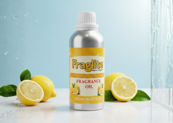 A Fraglite Lemon Fragrance Oil aluminum bottle standing on a white surface with fresh whole and halved lemons against a soft blue background.