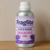A 500 ml silver bottle of Fraglite Lavender Fragrance Oil with a purple label and lavender flower graphics on a wooden shelf.