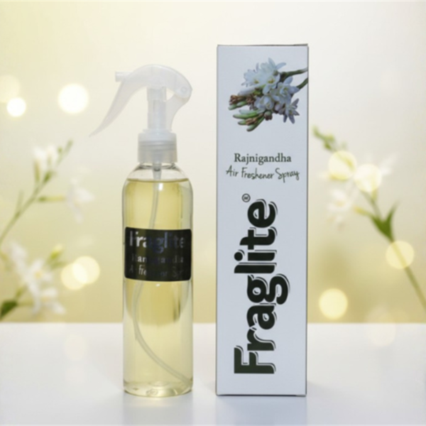 A Fraglite Rajnigandha spray bottle and box set against a soft, glowing background with white tuberose flowers.