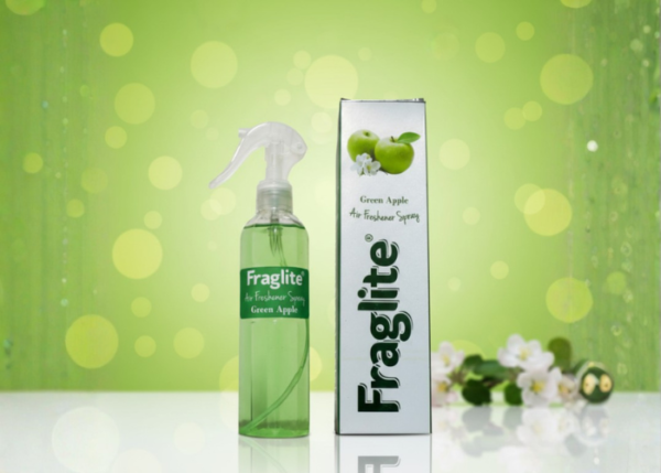A green Fraglite spray bottle and box against a soft green background with green apples and white apple blossoms.