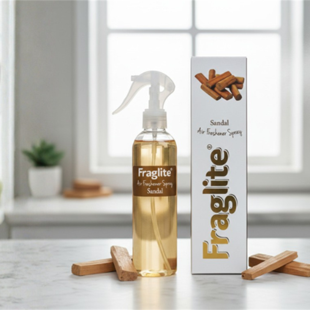 A Fraglite Sandal spray bottle and box on a marble counter with sandalwood sticks scattered around the base.