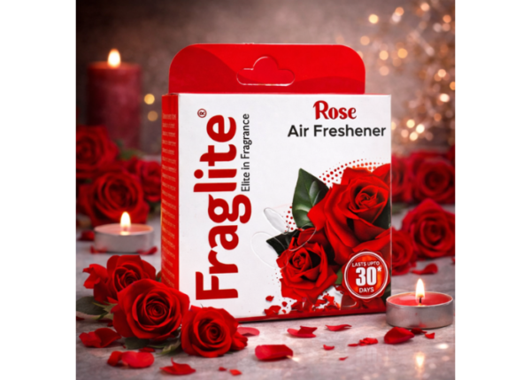 A box of Fraglite Rose Air Freshener placed among red roses and lit tea light candles in a warm, dimly lit environment.