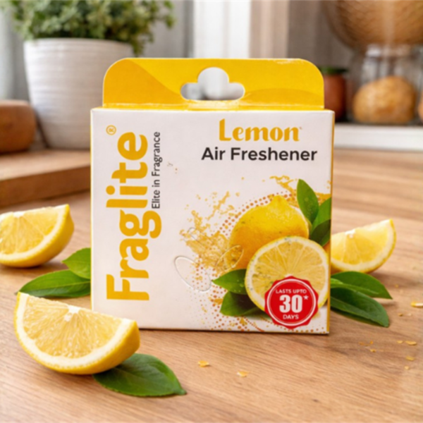 Fraglite Lemon Air Freshener box on a wooden kitchen table surrounded by fresh lemon slices and green leaves.