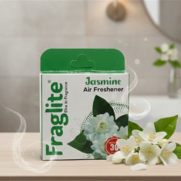 A box of Fraglite Jasmine Air Freshener sitting on a wooden surface next to fresh white jasmine flowers in a bright bathroom setting.